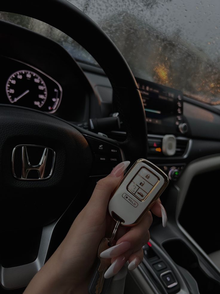 a woman holding a remote control in her hand while driving a car on a rainy day