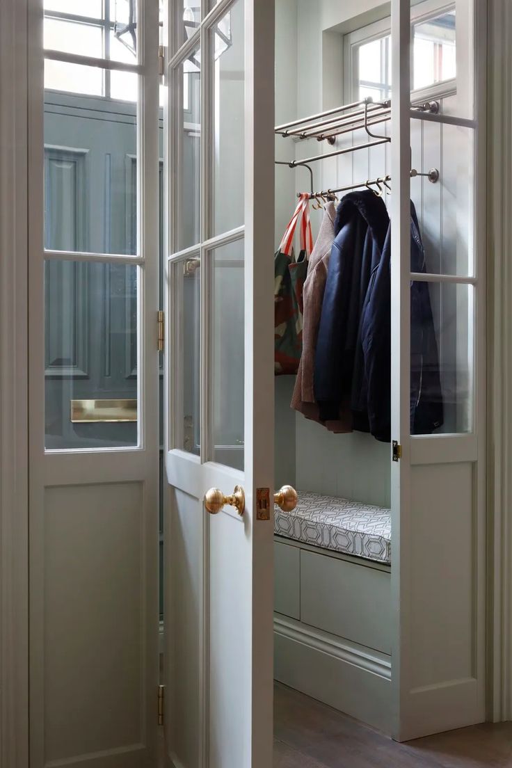 an open door leading to a walk in closet with clothes hanging on hooks and coat racks