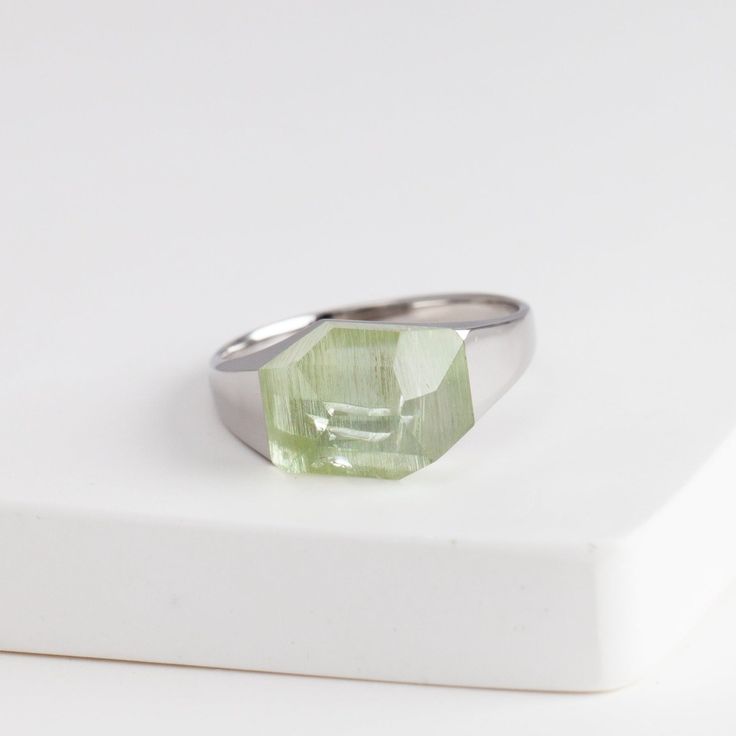 Description Bororo's signature rock ring in a smaller size with a beautiful green aquamarine stone from Brazil. Mini rock rings are perfect for those who love the innovative design of rock rings and want to wear it every day. The irregular geometrical cut of the stone makes this ring edgy and contemporary. The pieces in the rock series are made by applying the Japanese traditional method 'Dozuri'. This technique shapes the ring when the stone and metal are attached to create its seamless look. Every single rock ring is unique because from the designer's selection of the rough stone to the traditional craftsman cutting and smithing the ring, every action is based on the shape of each individual stone. Details Rhodium Plated Sterling SilverGreen Aquamarine – Approximately 11 x 8mm (size vari Modern Peridot Rings For Anniversary, Modern Polished Rings With May Birthstone, Modern White Gold Crystal Ring With Gemstone, Modern Green Jewelry For Anniversary, Modern Crystal Ring With Large Stone, Modern Peridot Jewelry For Gift, Modern Peridot Jewelry As A Gift, Modern Moonstone Ring With Large Stone, Modern Polished Emerald Ring Gift