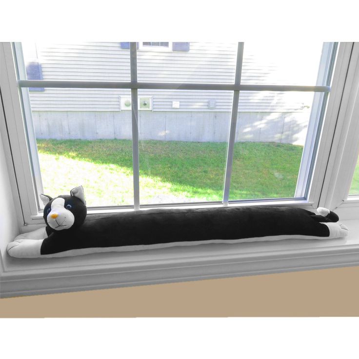 a black and white cat laying on top of a window sill