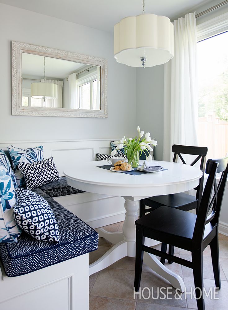 a white table with blue and white pillows on it in front of a large window