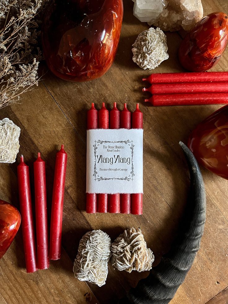 some red candles are sitting on a table next to rocks and other items that have been placed around them