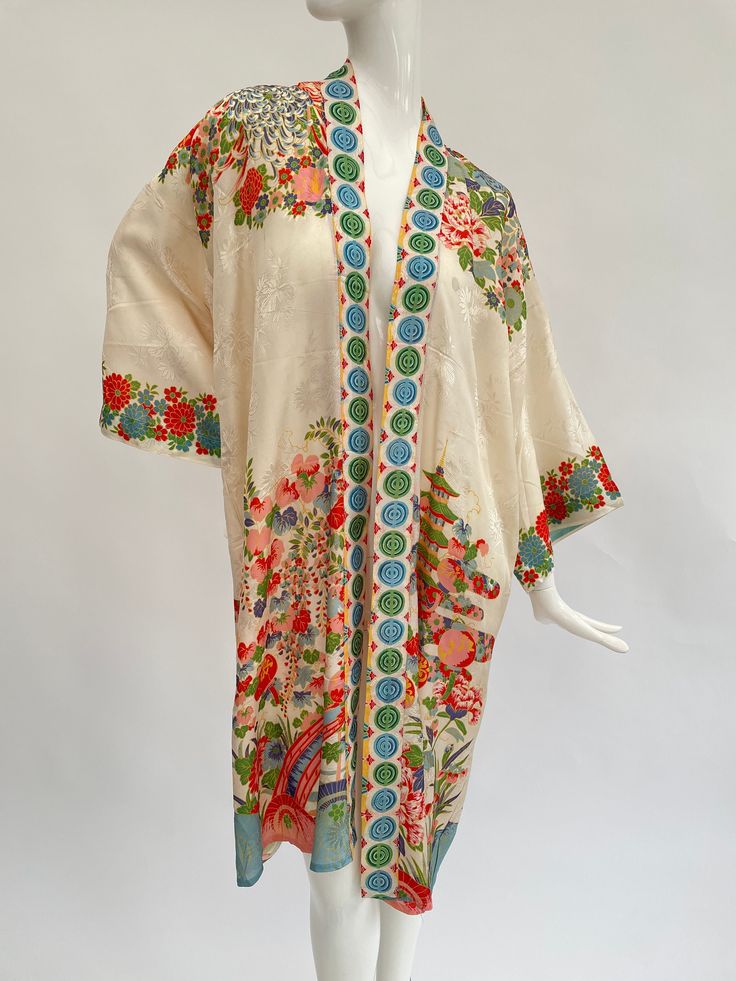 "This lovely antique 1930s Japanese export silky rayon robe is in a rare cream colour with soft complementary highlight colours including blue orange, green and white. It is a classic of its type, having a detailed design of flowers, a bridge and pagodas in a landscape. There are no ties, so this robe is designed to be worn open. I particularly like the unusual repeating geometric circle design on the front edges of this robe.  This is a free sized garment so will fit a variety of sizes. When laid flat, the length is approximately 40\" inches and from underarm to underarm across is approximately 25\" inches.  The condition is excellent overall, this looks to have hardly been worn and the colours are fresh and bright. On close inspection I can see a feint mark line to the front which I susp Vintage Multicolor Kimono For The Beach, Vintage Multicolor Kimono For Beach, Traditional White Floral Print Kimono, Traditional White Floral Kimono, Long Cream Spring Kimono, Vintage Silk Kimono For Summer, Summer Vintage Silk Kimono, White Kimono With Floral Embroidery, Vintage Multicolor Spring Kimono