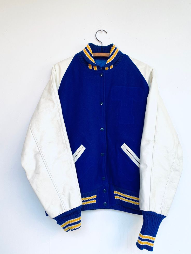 Vtg Letterman Jacket  White Leather Arms Blue Body Yellow and Blue Sleeve and Collar Trim Size Large Top of Collar to bottom Hem:32" Top of Collar to End of Sleeve:34" Pit to Pit:21.5" *At some point In the life of the jacket it used to have a front and back patch.If you look closely at the pictures you will see very faint evidence of where the patches used to be located. Blue Buttoned Outerwear For Streetwear, Vintage Fall Varsity Jacket With Button Closure, Fall Vintage Varsity Jacket With Button Closure, Vintage Cotton Varsity Jacket With Pockets, Vintage Varsity Jacket With Button Closure For Winter, Vintage Winter Varsity Jacket With Button Closure, Blue Varsity Jacket With Pockets, Navy Fitted Retro Outerwear, Fitted Navy Retro Outerwear