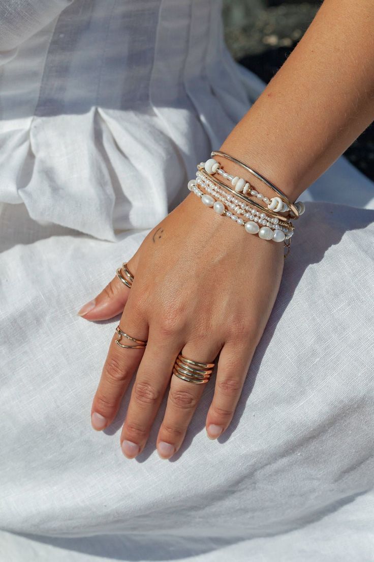 Beautified with an assemblage of lustrous white freshwater pearl beads, this 18k gold filled pearl bracelet alludes to the soothing sands of Hawaii's shores. Wear this gold pearl bracelet alone or stacked for a classically elegant look. ✦ DETAILS ✦✧ Name: Hiwahiwa (HEEvah HEEvah) - precious, beloved, indulged. ✧ Adjustable Length from: 6.5"-8".✧ White Freshwater Pearls.✧ 14kt Gold Filled Components, Extender, and Clasp.✧ All Ke Aloha Jewelry pieces come packaged thoughtfully, beautifully, and re Adjustable Stackable Pearl Bracelet, Dainty Pearl Stackable Beaded Bracelets, Dainty Stackable Pearl Beaded Bracelets, Dainty Stackable Pearl Bracelet, Adjustable Pearl Beaded Bracelets Stackable, Adjustable Stackable Pearl Beaded Bracelets, Everyday Stackable Pearl Bracelet, Gold Pearl Charm Bracelet For Beach, Gold Pearl Bracelet With Pearl Charm For Beach