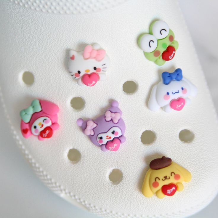 there are many different buttons on the back of a cell phone case that is decorated with hello kitty characters