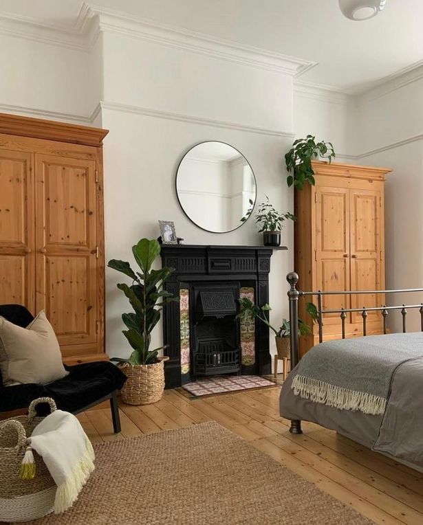 a bedroom with a bed, dresser and mirror in it's corner area next to a fireplace