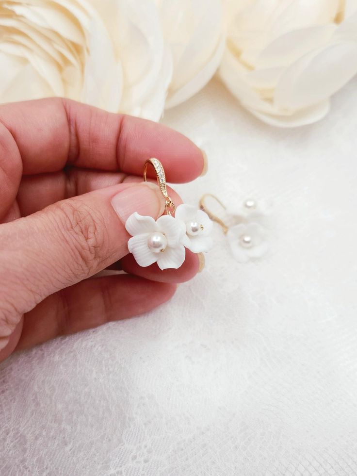 Soft white pearl deco ceramic double flower dangle style earrings with cubic deco gold or silver hook. Handmade and wire wrapped.  Nickel and Lead free.  Size.  3.2cm x 2.5cm Available in gold and silver finish. **The earrings may look bigger on the display model. Please refer to the actual size listed above. Returns and exchange details   Customer Satisfaction Guarantee: Below policy will replace standard ETSY policy- please read carefully before purchasing. If you are not satisfied with an item for any reason, I will provide a full refund less the actual shipping and handling charge (usually around $4.00). The return or exchange request must be made within 3  days from the actual delivery date. All returns must be postmarked within 3 business days of receiving a return authorization. Ple Delicate 3d Flower Dangle Jewelry, Elegant White Pearl Earrings With Flower Charm, Delicate Formal Jewelry With 3d Flowers, Dainty White Dangle Flower Earrings, Delicate 3d Flowers Jewelry For Formal Occasions, Delicate Flower-shaped Pearl Earrings With Ear Wire, Delicate Flower Shaped Pearl Earrings With Ear Wire, Elegant Jewelry With 3d Flowers For Anniversary, Delicate White Jewelry For Bridesmaid Gift