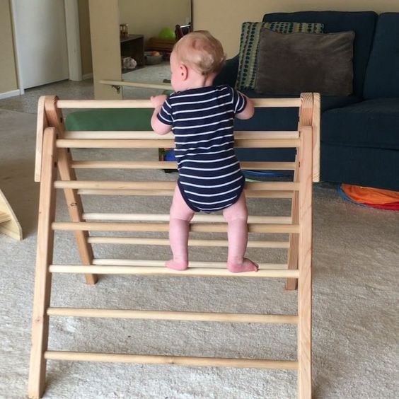 a baby standing on top of a wooden chair