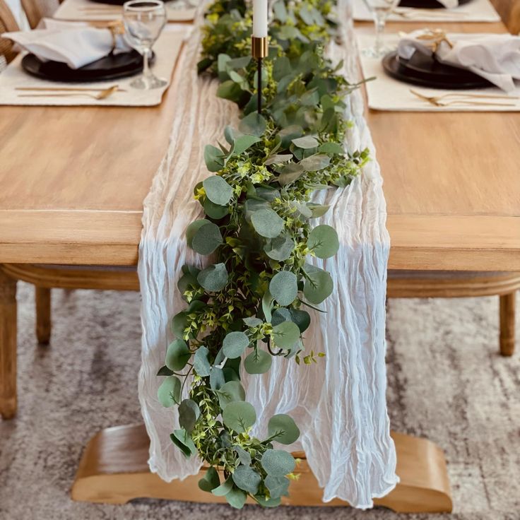 the table is set with greenery and place settings