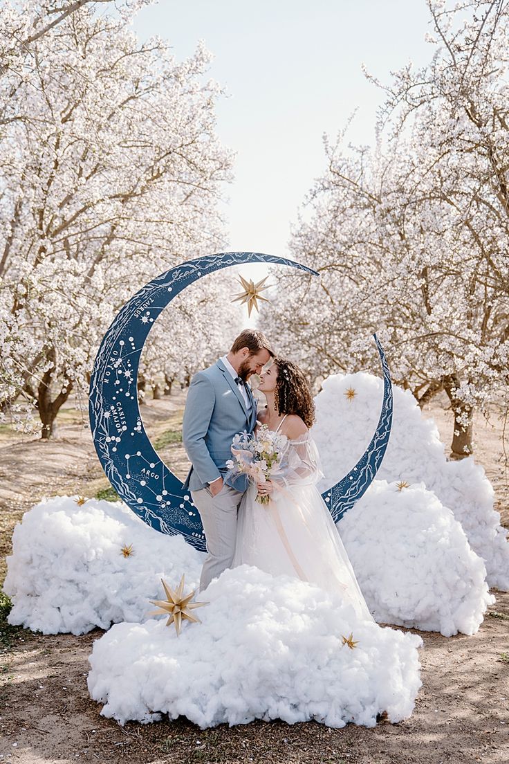 a bride and groom kissing in front of a crescent moon with snow on the ground