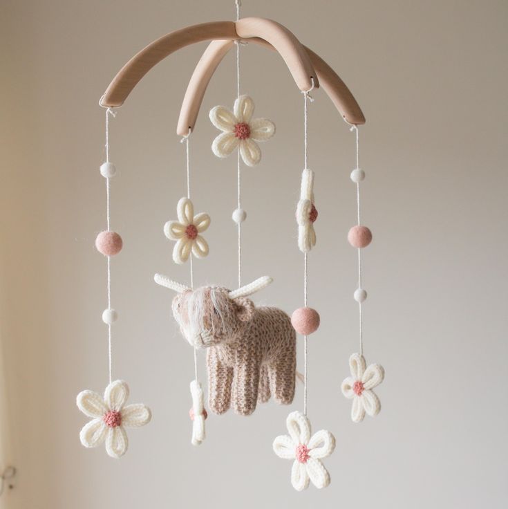 a crocheted unicorn mobile with flowers hanging from it's sides and a wooden stick in the middle