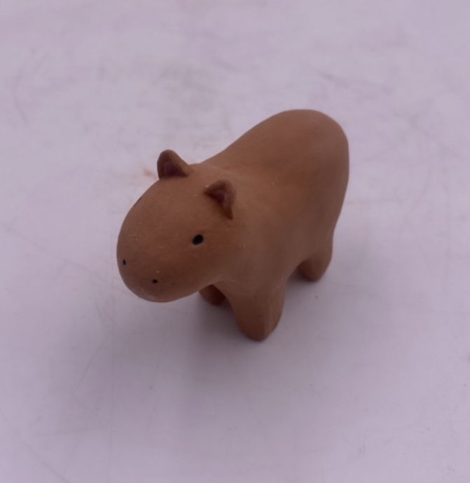 a small toy hippo is sitting on the floor in front of a white background