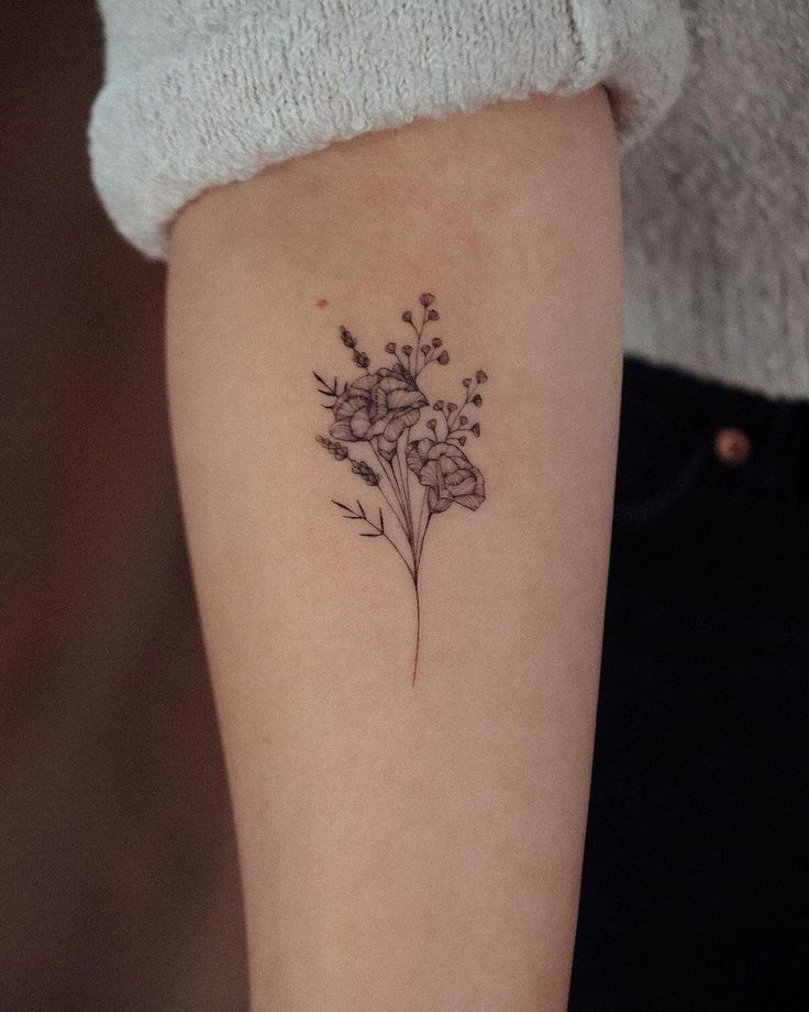 a small flower tattoo on the left arm