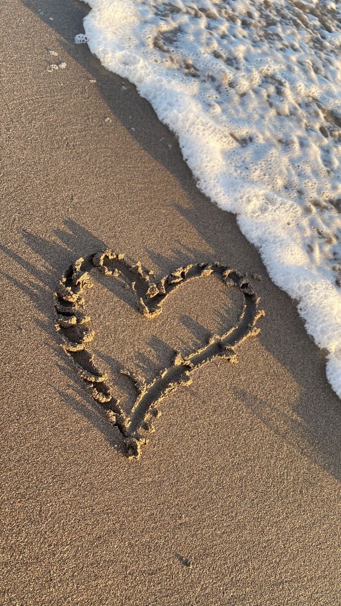 a heart drawn in the sand at the beach