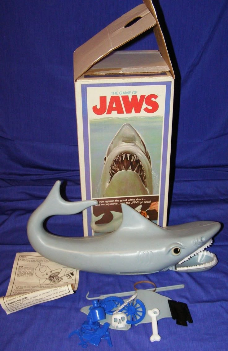 a toy shark with its mouth open next to it's box and instructions on how to use it