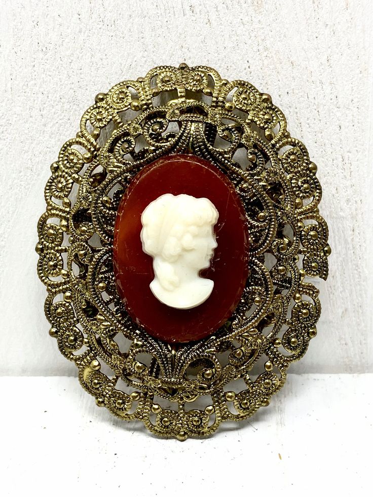 West Germany Filigree Two Tone White Cameo Brooch  This lovely piece can be worn on any occasion and is absolutely beautiful in the light, both inside and out, the perfect gift for anyone who loves vintage jewelry.  Colors and Shades may vary due to Lighting                            "Questions" Please read description carefully before buying to avoid confusion and cancellations. Please ask questions accordingly if needed. I do my best to answer emails promptly. - Measures Approx.  2" long - Each order comes shipped in a small drawstring pouch, all ready for     gifting. -If you are wanting to have this mailed as a gift to a special someone,  please write their address in the note section, otherwise it will be mailed to you. -If you would like to add a special typed note added to the orde Ornate Oval Filigree Brooches, Victorian Oval Filigree Brooches, Ornate Cameo Brooch For Anniversary, Ornate Cameo Brooches For Anniversary, Victorian Baroque Brooches As Gifts, Antique Cameo Brooches For Wedding, Antique Baroque Brooches For Wedding, Antique Gold Brooches From Vintage Collection, Antique Gold Brooches For Vintage Collection