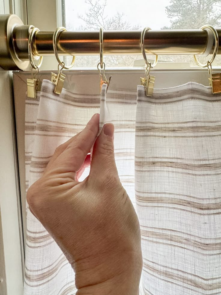 a hand is holding the curtain rod to open it