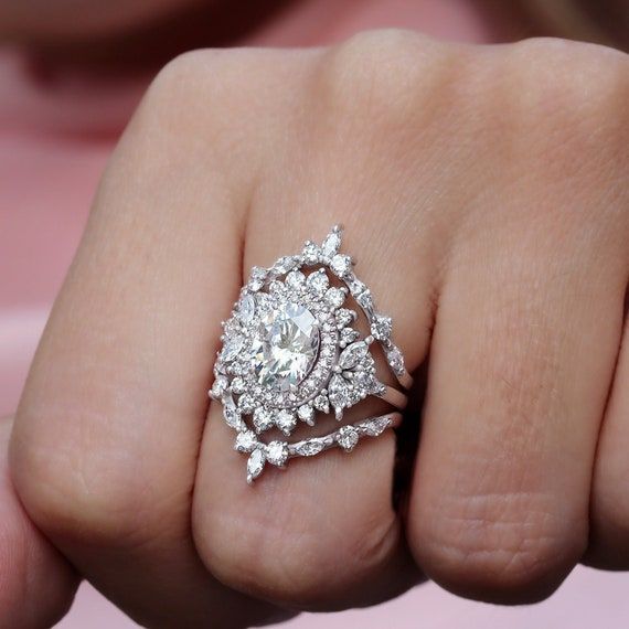 a close up of a person's hand with a diamond ring on their finger