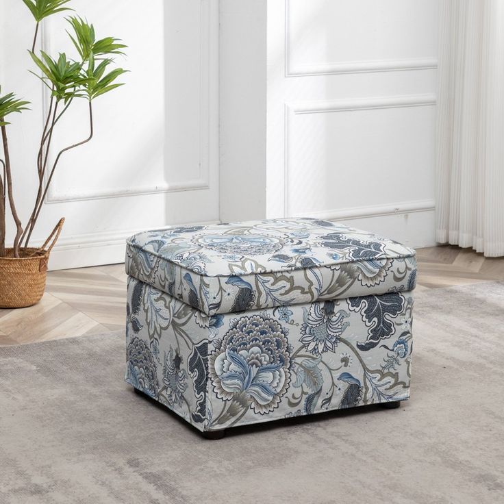 a blue and white ottoman sitting on top of a carpeted floor next to a potted plant