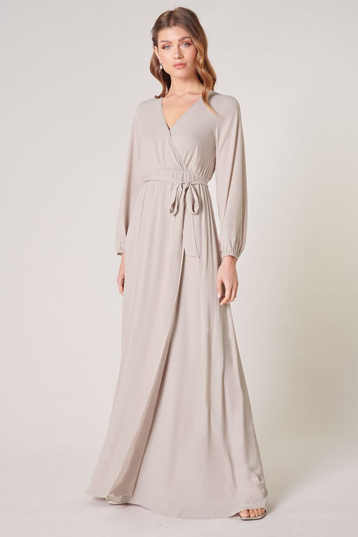 Warm and inviting, the Wholehearted Maxi Dress is a perfect combination of modest and sultry. Long balloon sleeves frame a surplice neckline separated by a tie at the waist, creating a forgiving faux wrap. The skirt maintains an airy and flowy shape that trails behind as you walk down the aisle. - Chiffon- Faux wrap- Keyhole- Elastic waist- Comes in 14 ColorsSize + Fit - Model is 5'9" and wearing size XS- Measurements taken from size S - Chest: 35"- Length: 63 1/4" Fabric Self: 100% PolyesterLin Flowy Belted Wrap Dress, Flowy Belted Wrap Dress With Surplice Neckline, Flowy Chic Wrap Dress For Fall, Flowy Belted V-neck Maxi Dress, Flowy Belted Maxi Dress With V-neck, Flowy V-neck Belted Maxi Dress, Flowy V-neck Dress With Surplice Neckline For Date Night, Fall V-neck Belted Maxi Dress, Flowy Belted Maxi Length Wrap Dress