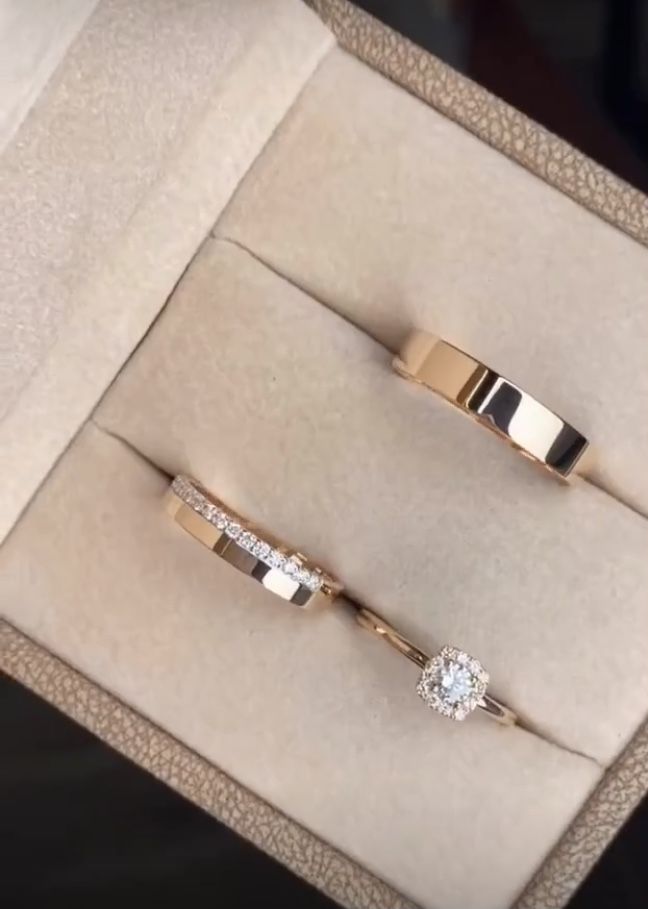 two wedding rings in a box with diamonds on the inside one is yellow gold and the other is white gold