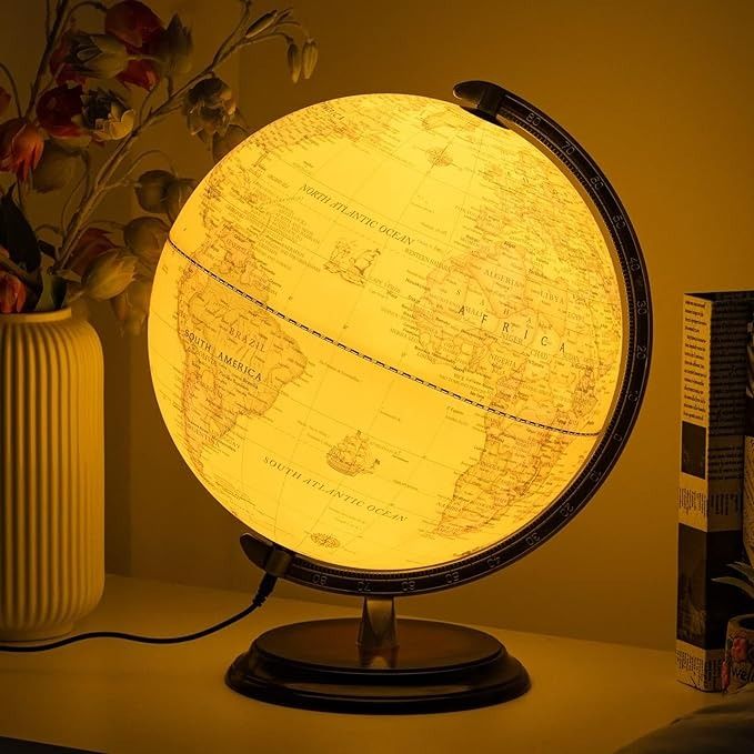 an illuminated globe sitting on top of a table next to a vase with flowers in it