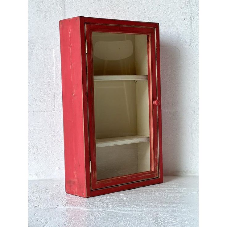 an empty red cabinet sitting against a white wall