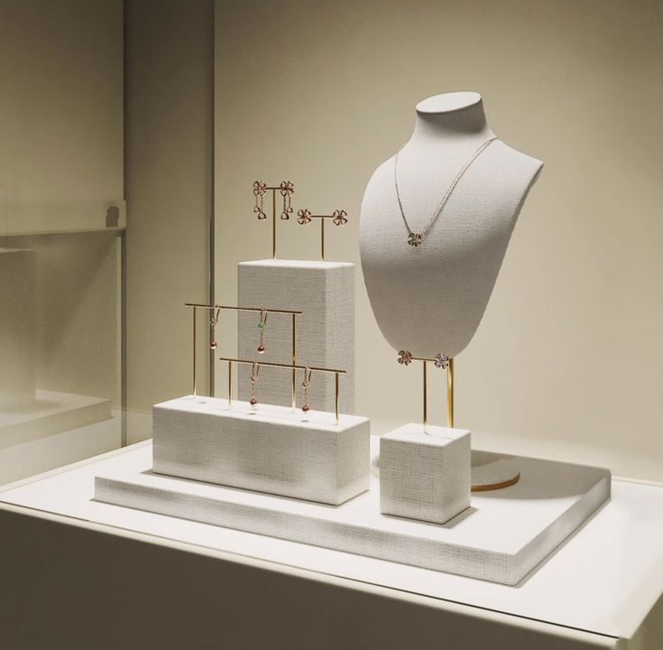 two white mannequins with necklaces on display in a museum exhibit case