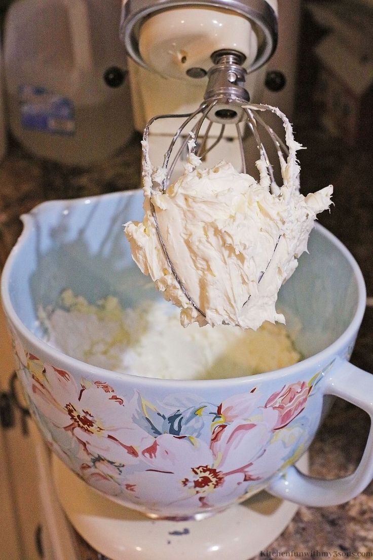 a mixer mixing cream in a bowl on top of a counter