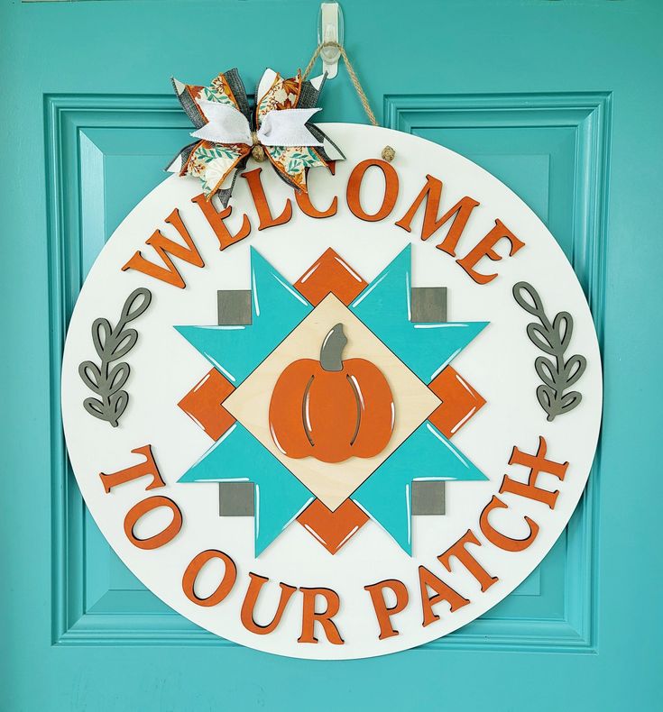 a welcome to your patch sign hanging on a blue door with an orange and white pumpkin