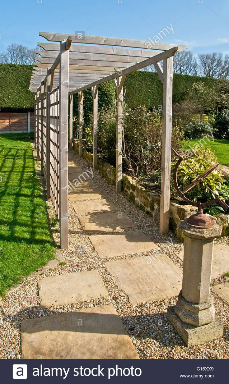 an outdoor garden with stone walkway and pergolated area - stock image