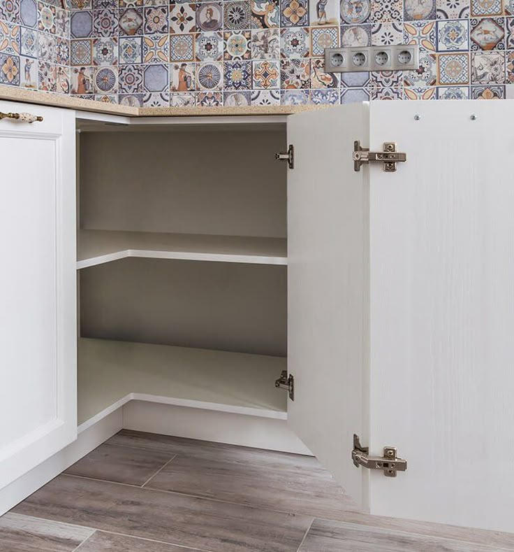 an empty cabinet in a kitchen with tile on the wall and wood flooring around it