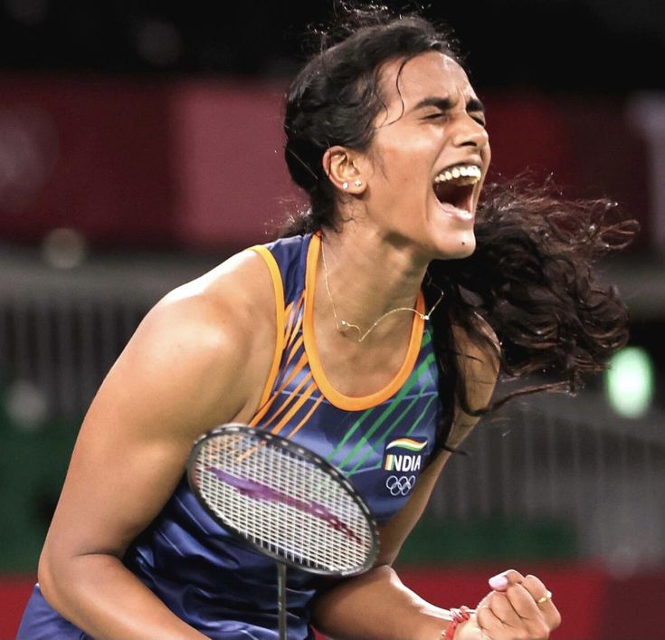 a woman holding a tennis racquet in her right hand and laughing at the same time