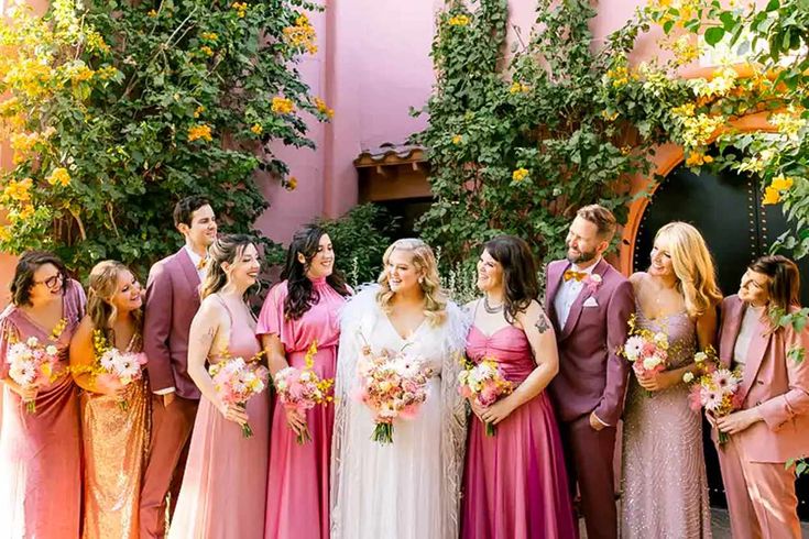 a group of people standing next to each other in front of some trees and flowers