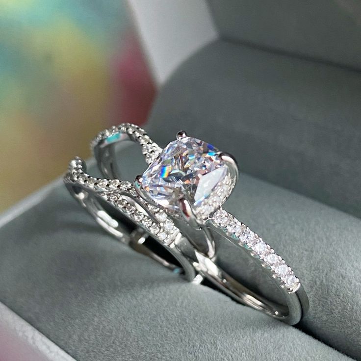 an engagement ring set with a cushion cut diamond in the center and side stones on each band