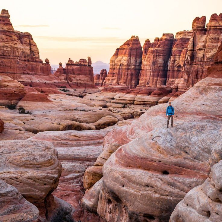 a man standing on top of a large rock formation in the middle of a desert