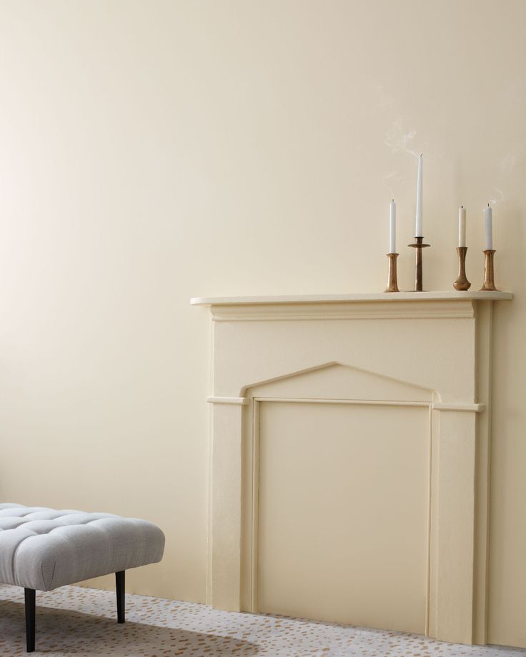 a living room with a white fireplace and two candles on top of the mantel