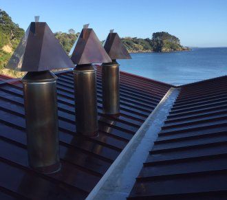 three lamps sitting on top of a roof next to the ocean with trees in the background