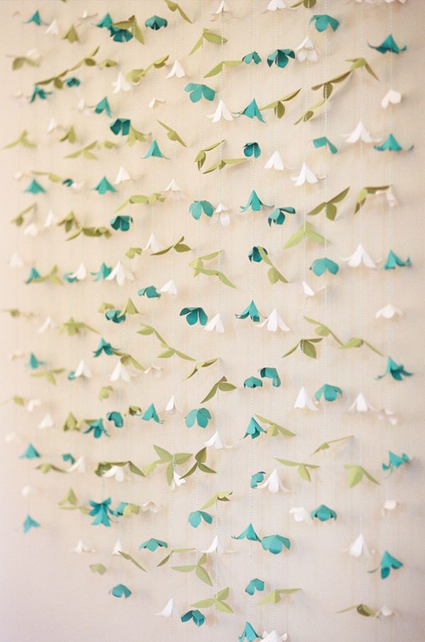 a white and blue wall hanging with paper birds on it's sides, in the shape of leaves