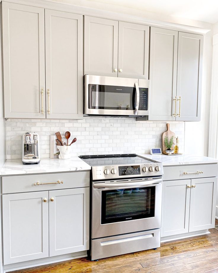 a kitchen with white cabinets and stainless steel stove top oven, microwave and toaster