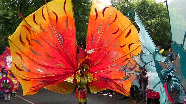 a woman with large orange and red umbrellas on her head walking down the street