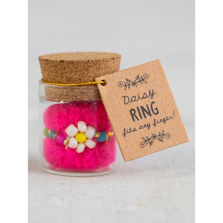 a small jar filled with pink and white flowers next to a tag that says daisy ring