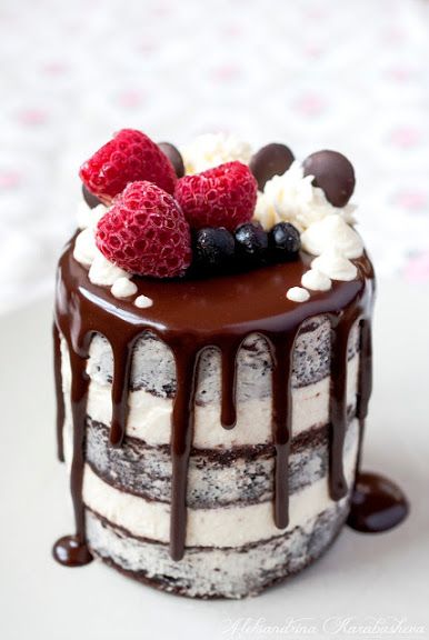 a chocolate cake with berries and cream on top, drizzled in chocolate