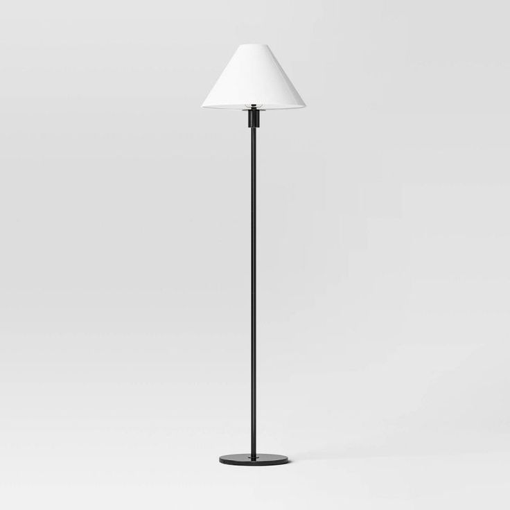 a black floor lamp with a white shade on the top and one light on the bottom