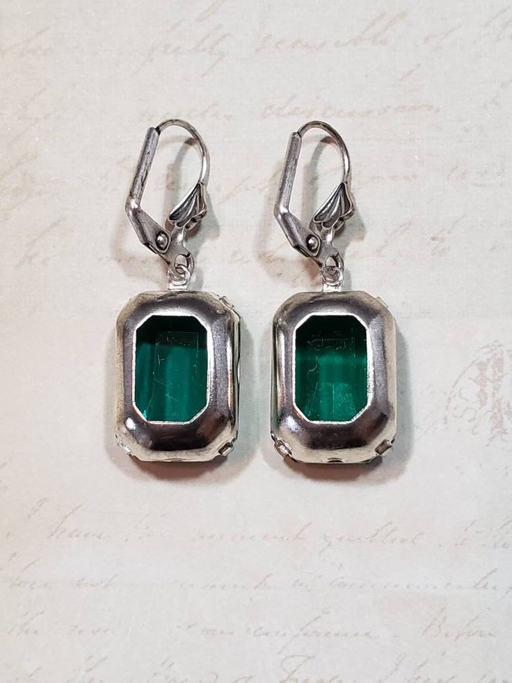 I love the clean simple lines and the sheer emerald green color of these Art Deco style estate earrings. They feature emerald green octagon rhinestone beads and silver plated leverback ear wires. These elegant earrings measure 1 1/4 inches long. Perfect for everyday or evening. ABOUT THIS COLLECTION What are the three style essentials Jazz Age flappers like Clara Bow, Louise Brooks, and Zelda Fitzgerald have in common? Red lipstick, bobbed haircuts, and fabulous dangle earrings. My Flapper Colle Green Art Deco Drop Earrings, Classic Green Clip-on Earrings, Art Deco Green Jewelry For Pierced Ears, Antique Green Jewelry For Evening, Vintage Style Emerald Drop Earrings, Retro Dangle Jewelry For Formal Occasions, Retro Green Drop Earrings, Vintage Emerald Drop Earrings, Vintage Emerald Jewelry With Matching Earrings