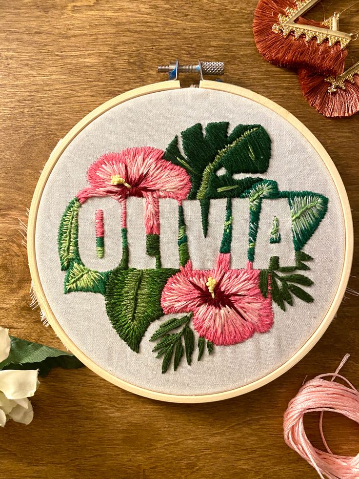 a cross stitch pattern with flowers and the word olliva in it on a wooden table