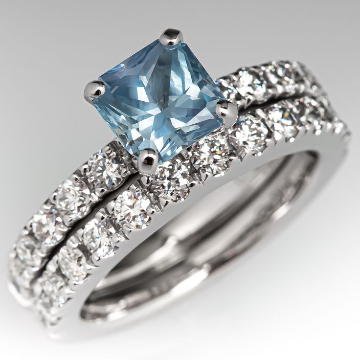 This two ring wedding set is soldered together. The engagement ring is centered with one (1) cut-cornered square modified brilliant cut natural Montana sapphire weighing 1.23 carats and set into a four-prong head. The top face of the engagement ring are each accented with a row of six (6), prong set, round brilliant cut diamonds. The wedding band is accented with a row of fourteen (14), prong set, round brilliant cut diamonds. The set measures 6.5mm at the top, rises 7.5mm above the finger, tape Gia Certified Square Cut Sapphire Diamond Ring, Wedding Sapphire Ring With Square Cut And Prong Setting, Square Cut Sapphire Ring With Prong Setting For Wedding, Square Cut Sapphire Diamond Wedding Ring, Wedding Sapphire Diamond Ring Square Cut, Sapphire Square Cut Wedding Rings, Square Cut Sapphire Rings For Wedding, Princess Cut Sapphire Ring With Diamond For Wedding, Princess Cut Sapphire Diamond Wedding Ring