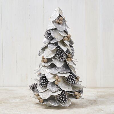 a white christmas tree made out of silver tinsel and pineconis on a table