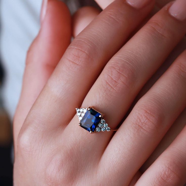 a woman's hand holding a ring with a blue and white stone in it